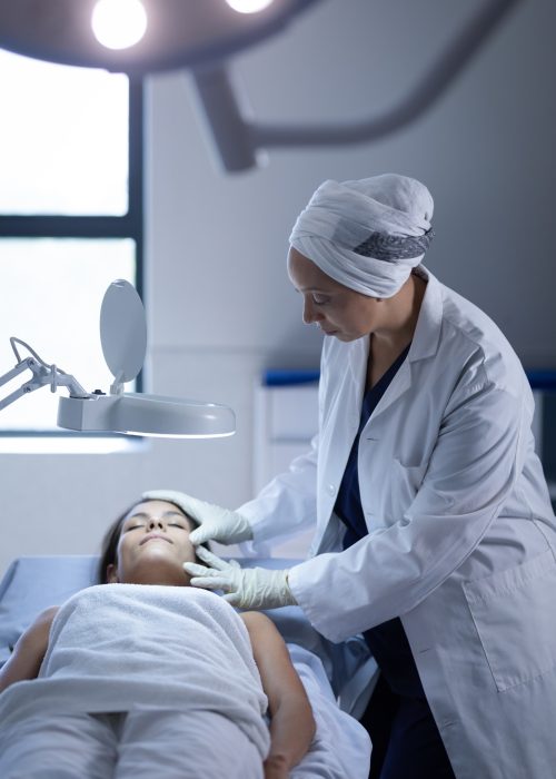 Mature female surgeon examining her patient during a plastic surgery in clinic